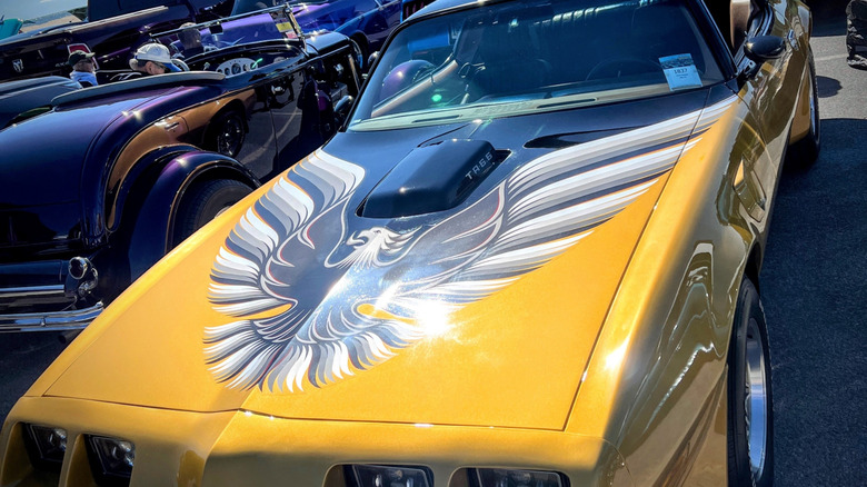 gold Pontiac Firebird with black and silver hood bird emblem