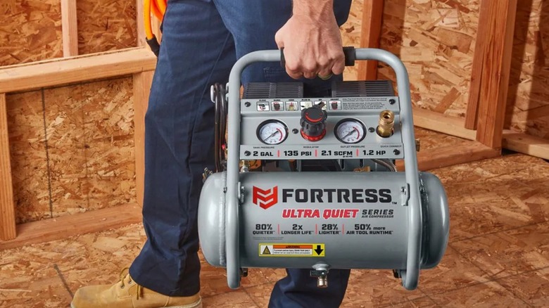 A person carrying a Fortress air compressor from Harbor Freight.