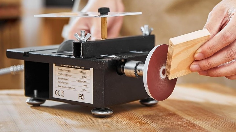 man using mini table saw with drill chucks