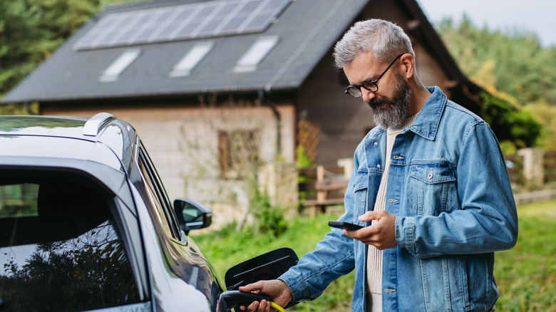 A guy charging his car using solar panels