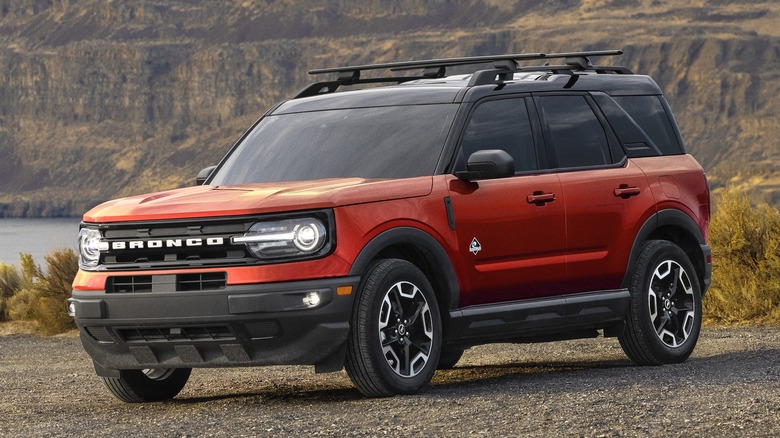 Orange 2022 Ford Bronco Sport parked on dirt with cliffs in the background