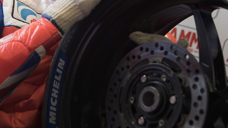 Close-up of a Red Bull motorcycle rider feeling the edge of a tire with a gloved hand.