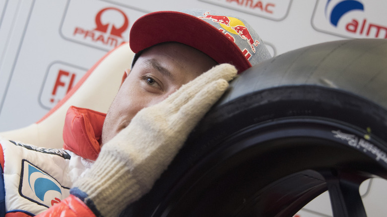 Close-up of a Red Bull motorcycle rider feeling the edge of a tire with a gloved hand.