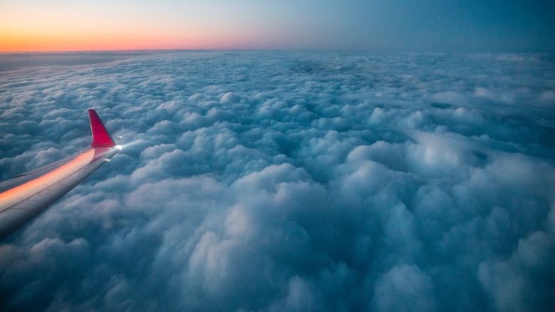 Airplane wings near clouds at sunset