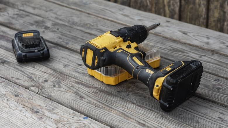 Cordless drill with battery detached on a wooden table