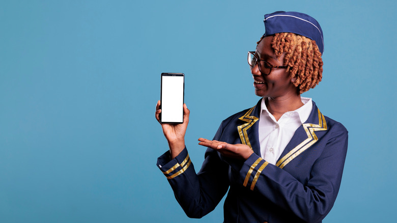 Flight attendant pointing at a mobile phone