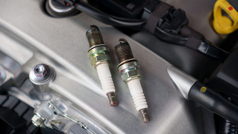 Pair of blackened spark plugs resting on engine timing cover