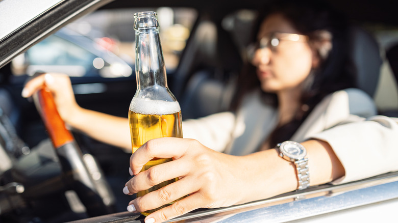 Woman holding beer bottle while driving