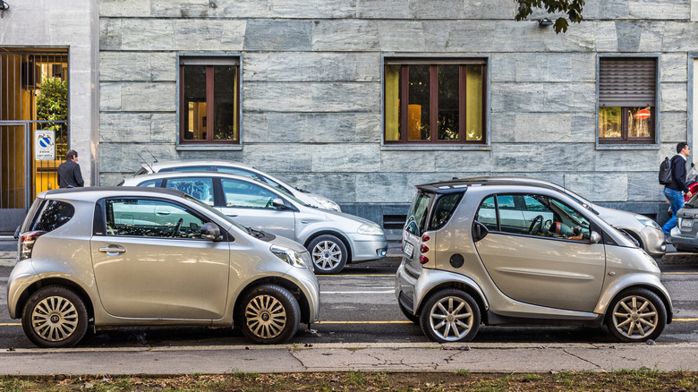 Toyota iQ parked behind Smart Fortwo in European city, right-side view