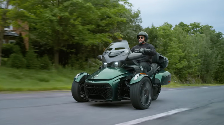 A green 2026 Can Am Spyder RT on the move, front 3/4 view
