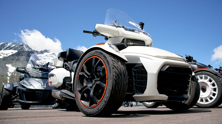 A white Can Am Spyder next to some other Can Am three wheelers in Austria, front 3/4 view, up-close low angle