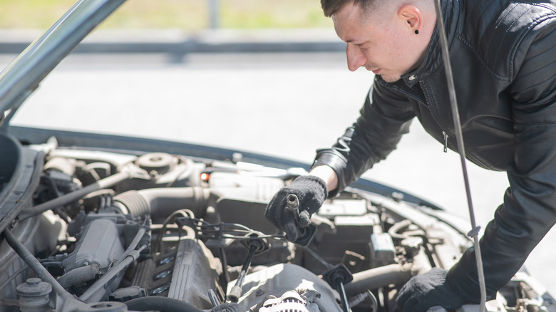 A person checking the spark plugs in their vehicle.