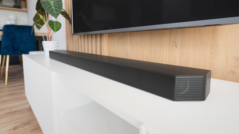 A soundbar in kept below a TV on a table
