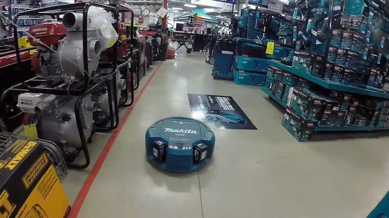 A Makita DRC200PT cleaning a large retail warehouse floor