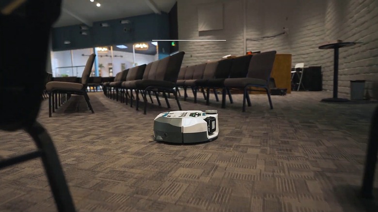 Makita DRC300 robot vacuum working to clean the carpet of a large venue space