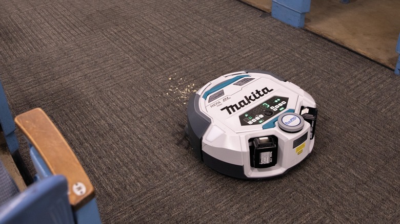 The Makita DRC300PT robotic vacuum cleaning crumbs off a carpet