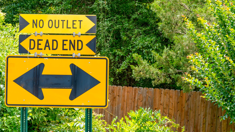 Road signs for No Outlet, Dead End, and opposing left and right arrows.