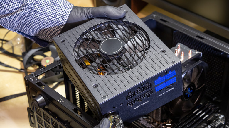 Person installing a large PSU into a desktop PC tower.