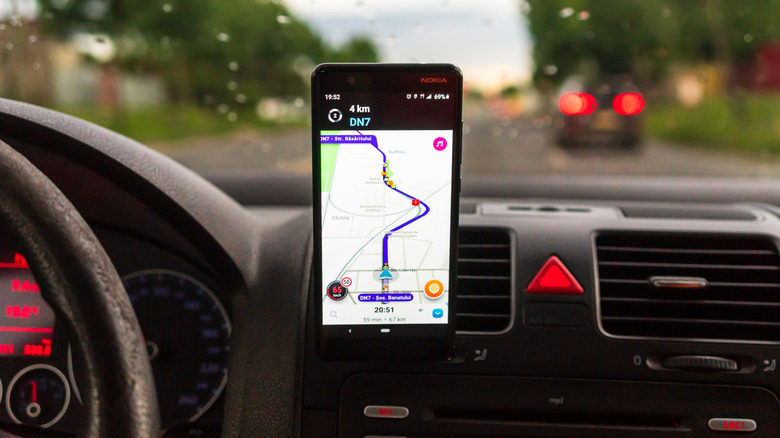 Driving and using Waze maps application on smartphone on car dashboard