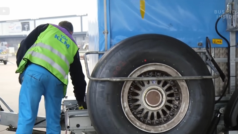 A man is changing an airplane tire