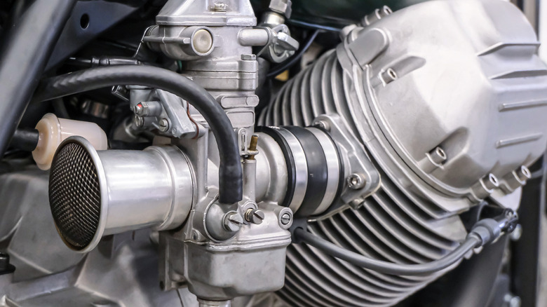 Close-up of a motorcycle carburetor with a polished velocity stack on a custom engine.