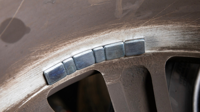 Close up of square wheel weights on brown car wheel