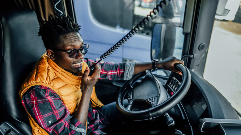 Male truck driver using radio to contact other convoy drivers.