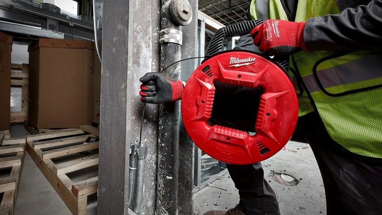 Person using the Milwaukee Tool steel fish tape to run wire through conduit.