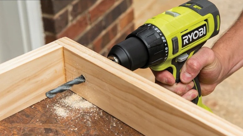 Using the Ryobi 18V One+ cordless drill to drill a hole in a board.