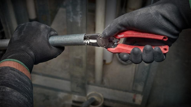 A person with gloves using Milwaukee pliers.
