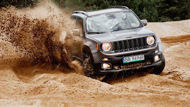 jeep driving through sandy mud path