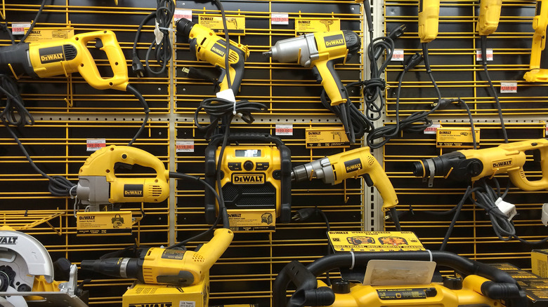 A large display of yellow DeWalt corded tools on a wall board