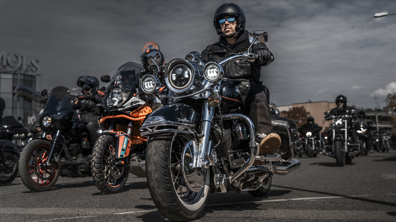 A motorcycle club featuring several people on expensive bikes with dark background