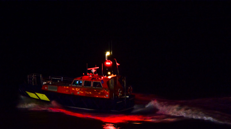 Boat displaying red lights at night.