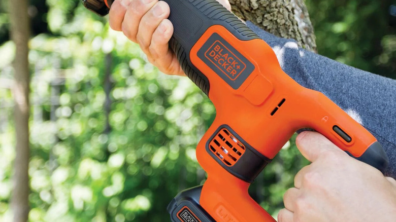 Hand holding a power tool with Black and Decker battery connected