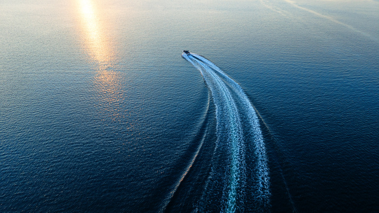 Boat on water with wake trailing behind it.