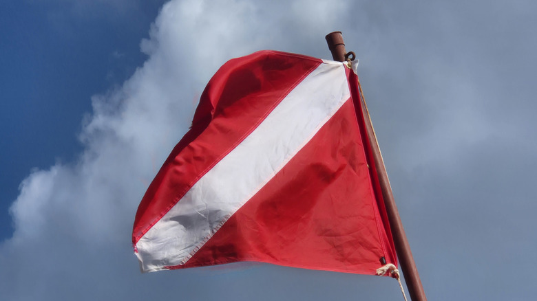 Red and white diver-down flag against a blue sky