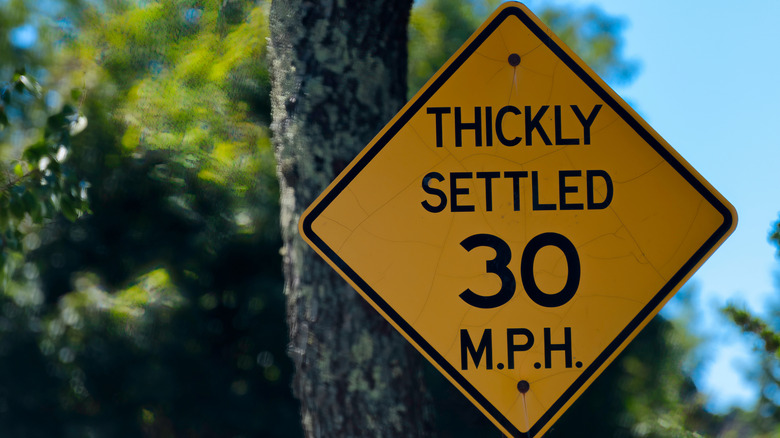 A yellow sign declaring a speed limit of 30 MPH in a thickly settled area