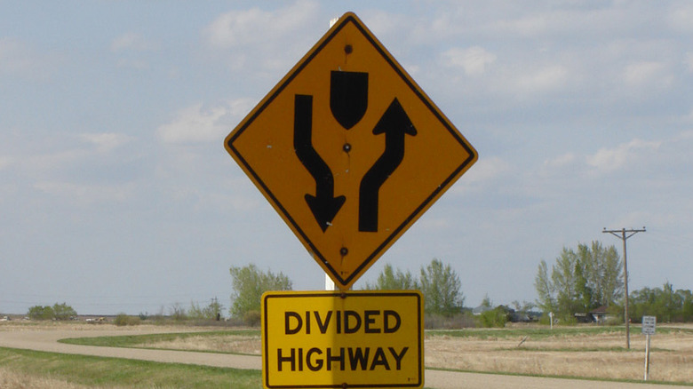 divided highway begins road sign