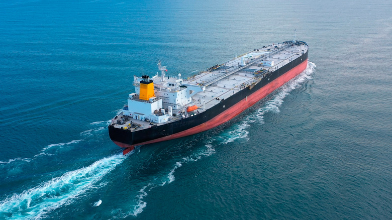 large freighter sailing away from camera on calm sea