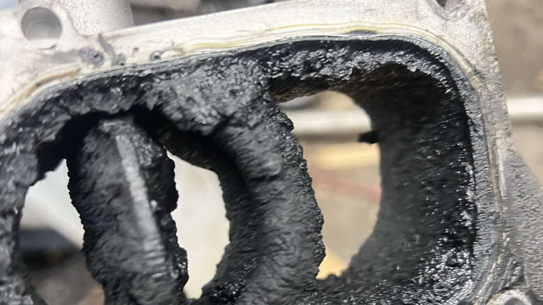 A close-up of a diesel engine intake manifold with a lot of carbon buildup