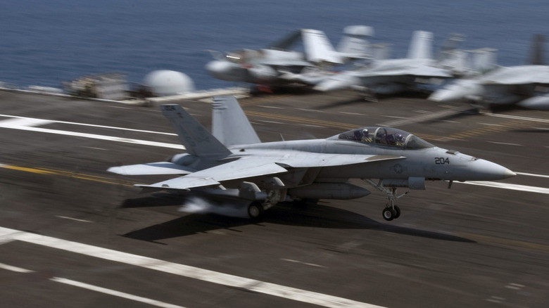 An F/A-18 Hornet landing at high speed on an aircraft carrier