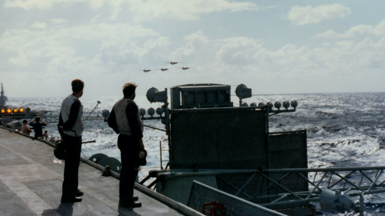 Two crew members standing behind the optical landing system on the aircraft carrier HMAS Melbourne