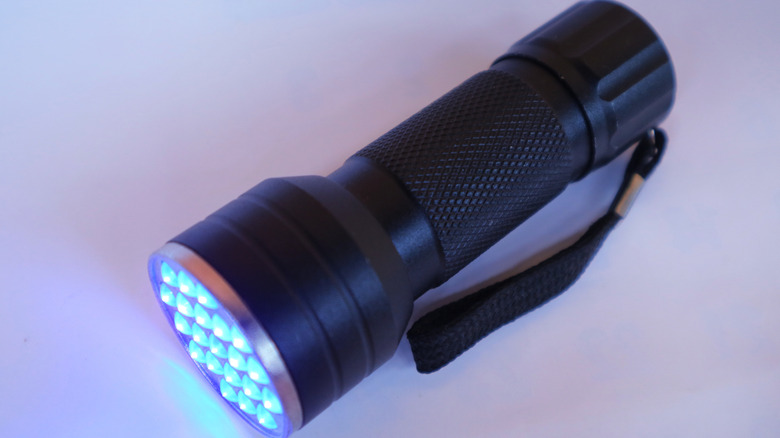 A black LED flashlight against a pink-white background
