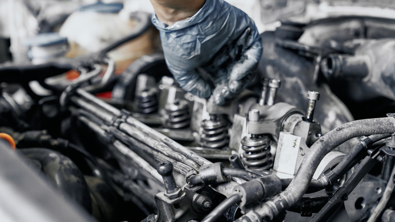 Close up of nozzles in car diesel engine with mechanic's hand
