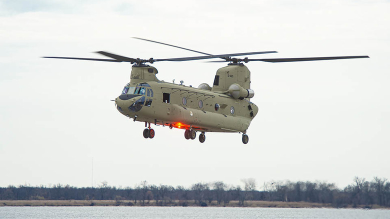 A Royal Netherlands Air Force CH-47 Chinook helicopter hovering above a waterbody.