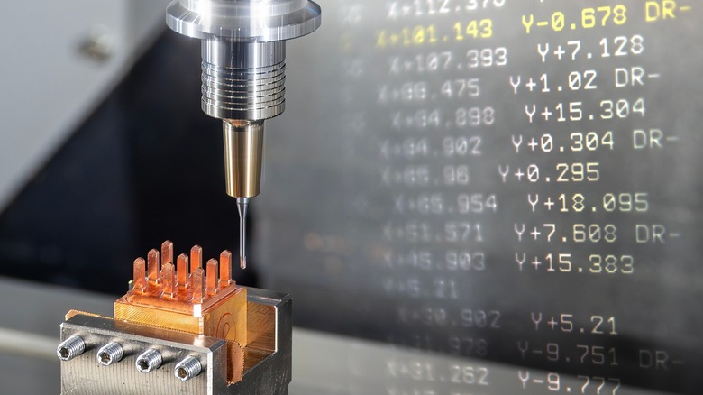 A CNC machine creating a workpiece while showing some of the program code.
