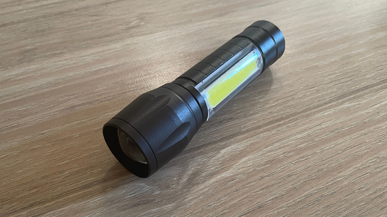 A modern black LED flashlight with COB side light