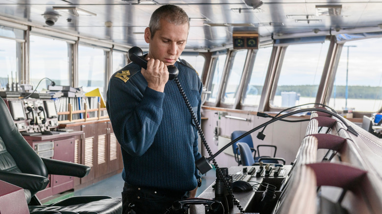 Deck Officer on a ship's bridge using the radio.