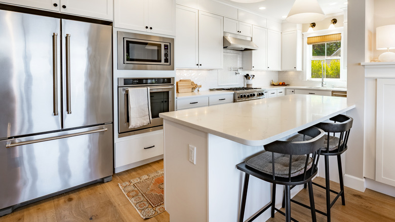A wide silver counter-depth fridge in an airy white kitchen with a kitchen island
